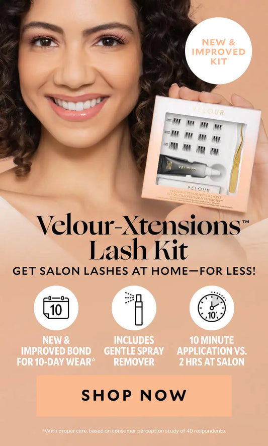 Smiling woman with curly hair holding a boxed Velour-Xtensions Lash Kit. The packaging displays lashes, a bonding adhesive, and applicator tool. Text on the image highlights “Velour-Xtensions Lash Kit – Get salon lashes at home—for less!”, “New and improved kit,” “New and improved bond for 10-day wear,” and “Includes gentle spray remover.” A peach-colored “Shop Now” button appears at the bottom.